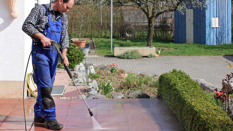 A man pressure washing a patio.