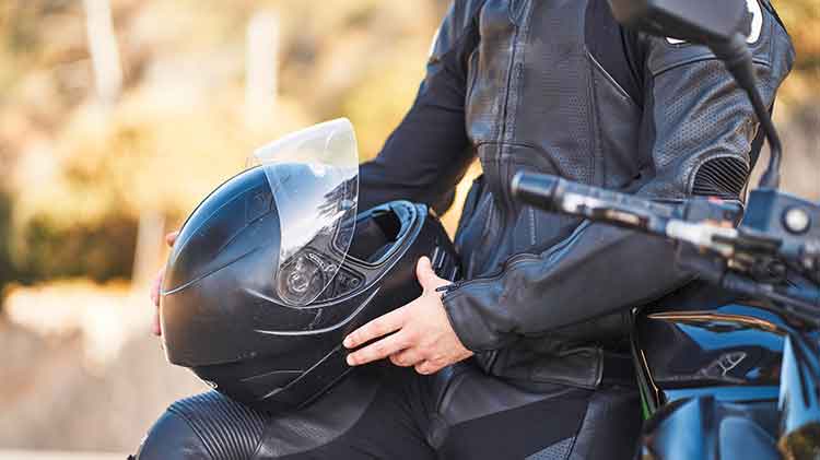 Man sitting on motorcycle holding his helmet.
