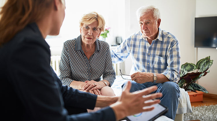 A woman and older couple talking in a living room.