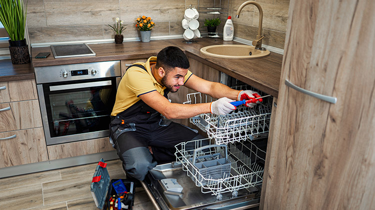Plumber doing an appliance repair on a dishwasher.