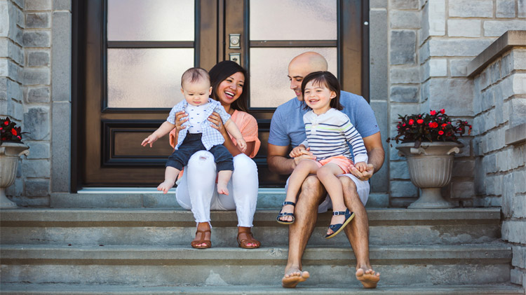 Young family sitting on their front porch steps.