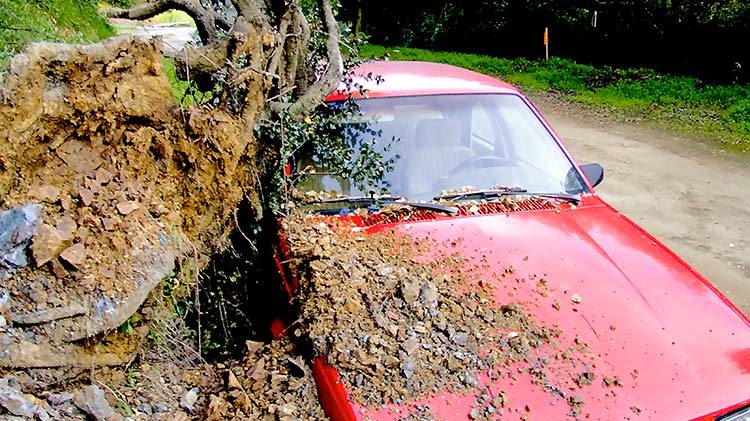 Red car covered with debris from a landslide.