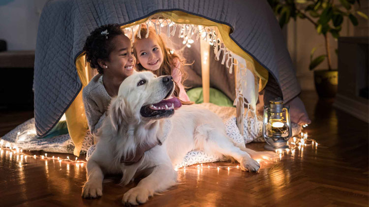 Happy little girls relaxing with golden retriever.