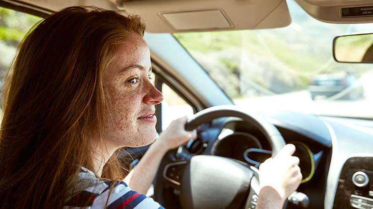 Teenage girl driving with both hands on the wheel.