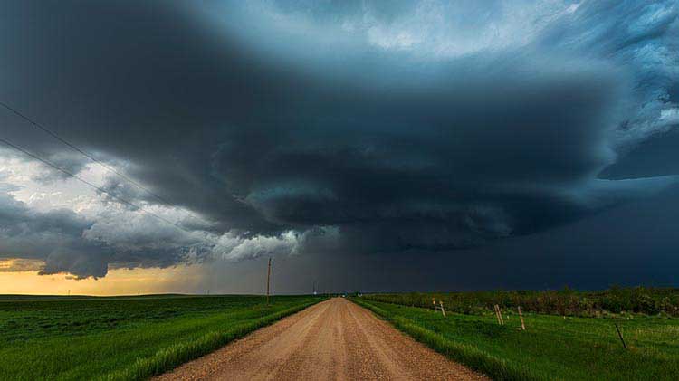 Dark storm clouds above a rural road and fields that have the potential to spawn a tornado.